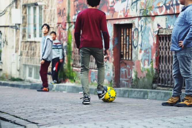 Straßenfußball in der U8 und U9, Kinder spielen auf Kopfsteinpflaster Fußball. Vorbild für F-Jugend Training
